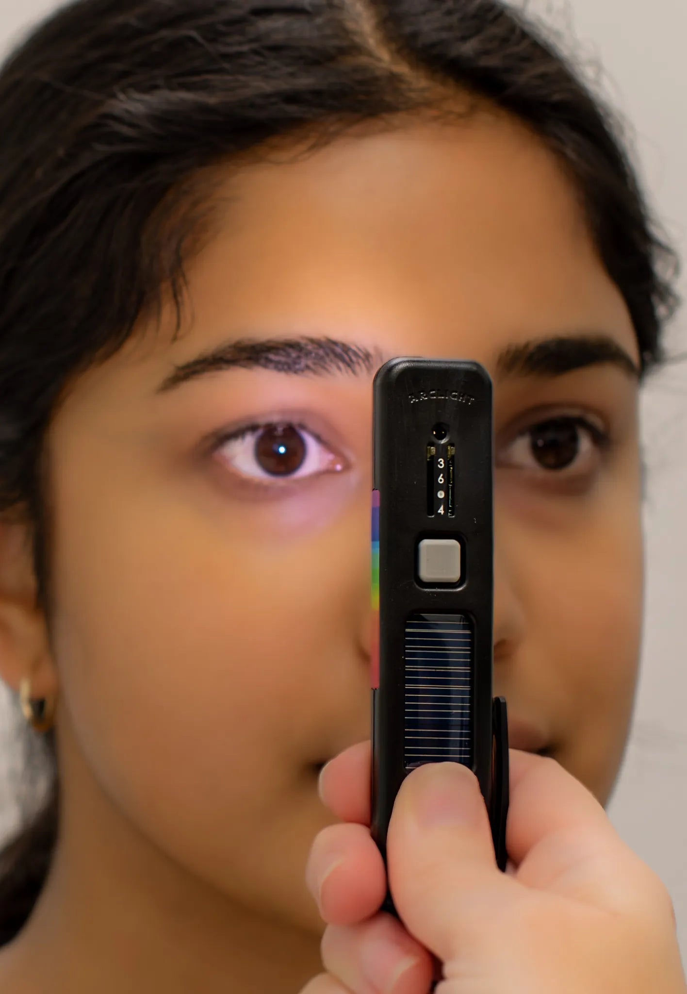 A person using the Arclight device to examine the eye, showcasing its compact design and utility for eye health diagnostics.